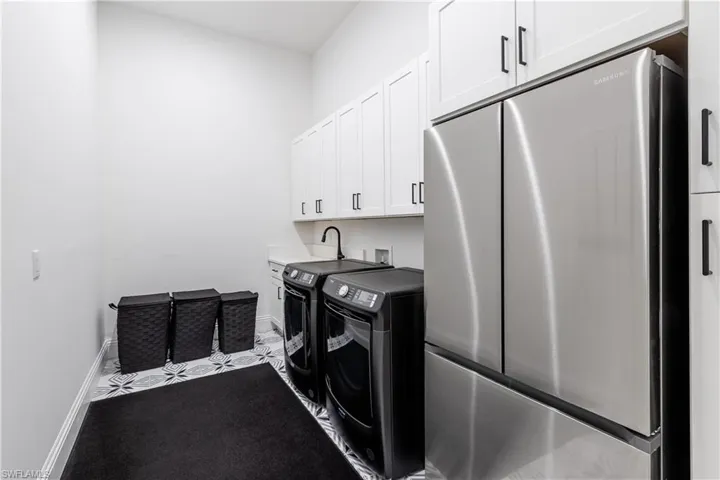 Laundry room featuring cabinet space, washing machine and dryer, and tile patterned flooring