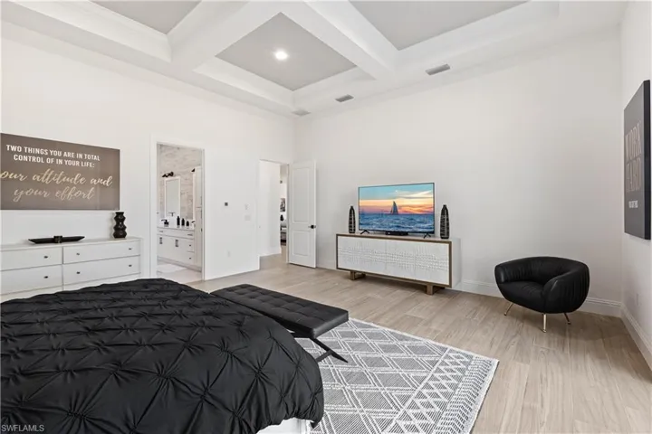 Bedroom with coffered ceiling, light wood-type flooring, ornamental molding, and ensuite bathroom