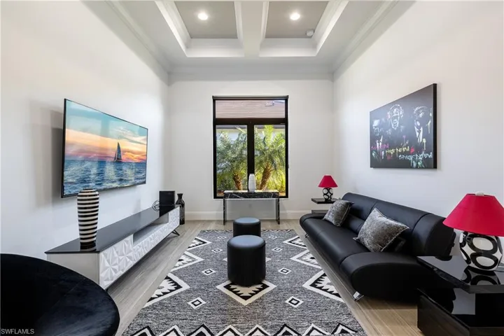 Living room with coffered ceiling, ornamental molding, light wood-style floors, and recessed lighting