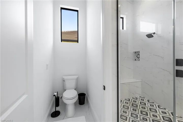 Bathroom featuring a marble finish shower and marble look tiles