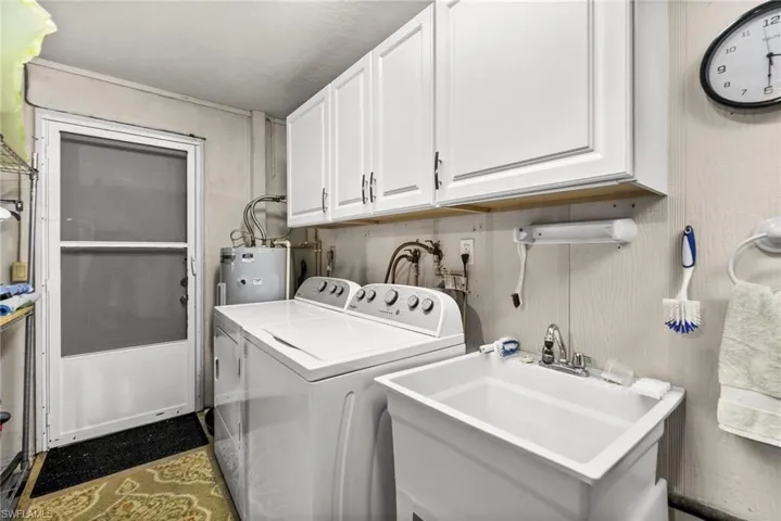 Washroom featuring washer and dryer, water heater, and cabinet space