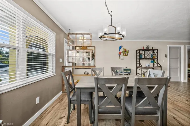 Dining area with light wood-type flooring, ornamental molding, and a chandelier