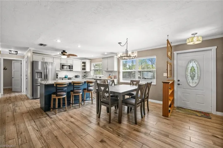 Dining area featuring ceiling fan, crown molding, a chandelier, a textured ceiling, and light wood-style floors