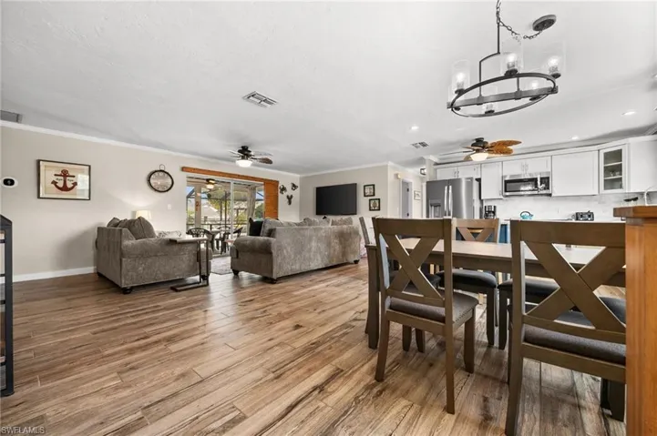 Dining room with ceiling fan, ornamental molding, light wood-style floors, a chandelier, and recessed lighting