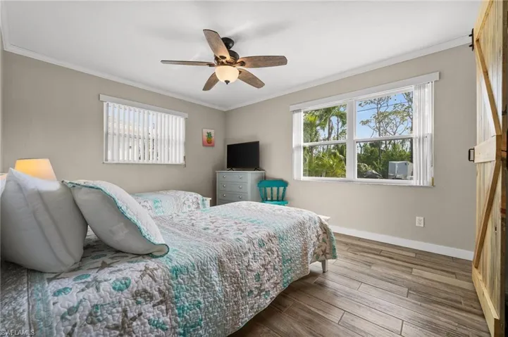 Bedroom with crown molding, wood finished floors, and a ceiling fan