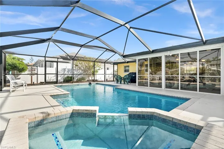 View of swimming pool featuring a pool with connected hot tub, a sunroom, glass enclosure, and a patio area