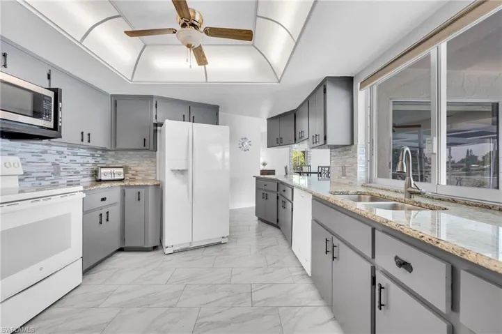 Kitchen with light gray cabinetry, granite-finish countertops, and a full tile backsplash