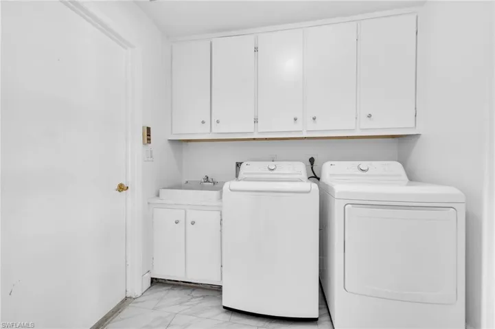 Dedicated laundry room featuring upper storage cabinetry, an integrated sink basin with lower cabinetry, and tiled flooring