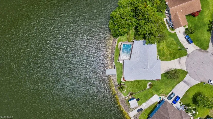 Waterfront property featuring an in-ground swimming pool, private boat dock, and lush green landscaping