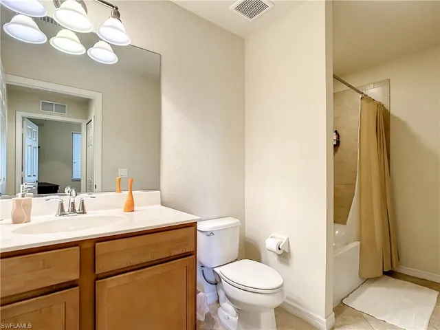 Full bath featuring shower / bath combo, vanity, and light tile patterned floors