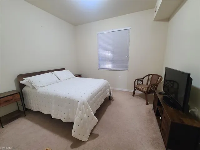 Bedroom with light colored carpet and baseboards