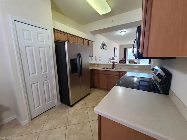 Kitchen with appliances with stainless steel finishes, light countertops, light tile patterned floors, and brown cabinets