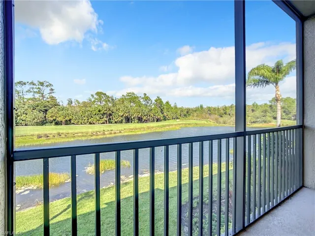 Balcony featuring view of wooded area, a sunroom, and a water view