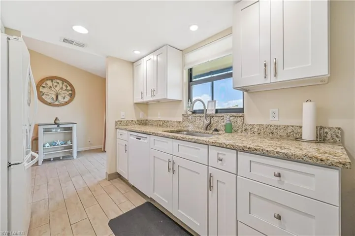 Kitchen with white cabinets, white appliances, light stone counters, recessed lighting, and wood finish floors