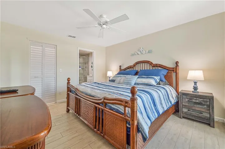 Bedroom featuring ceiling fan, a closet, light wood-style floors, and ensuite bath