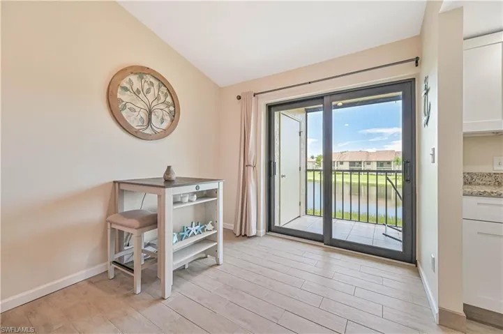 Doorway to outside with vaulted ceiling, wood finished floors, and a water view