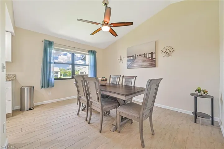 Dining room featuring light wood-style flooring, vaulted ceiling, and a ceiling fan