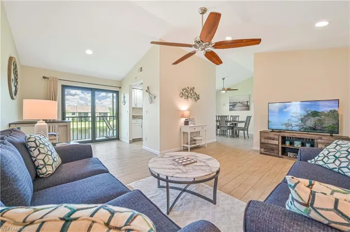 Living room with light wood finished floors, high vaulted ceiling, recessed lighting, and ceiling fan