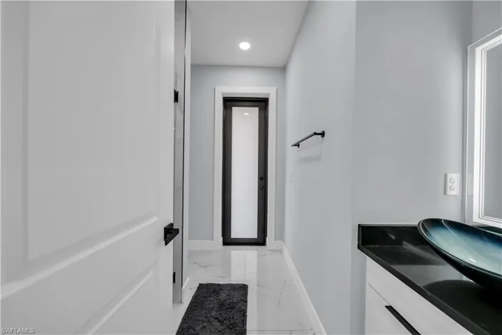 Bathroom with vanity, light marble finish floors, and recessed lighting
