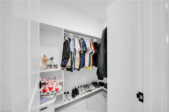 Walk in closet featuring light marble finish floors