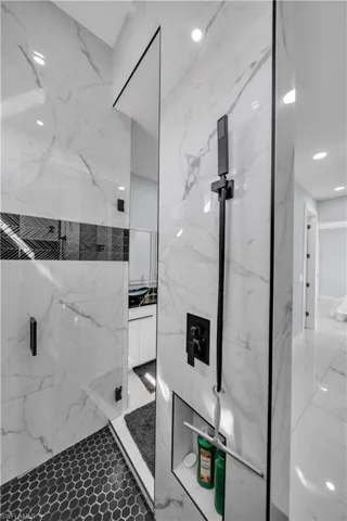 Full bathroom with a marble finish shower, vanity, and recessed lighting