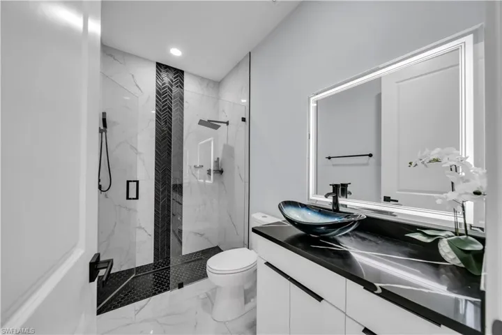 Full bath with vanity, a marble finish shower, recessed lighting, and marble finish floors