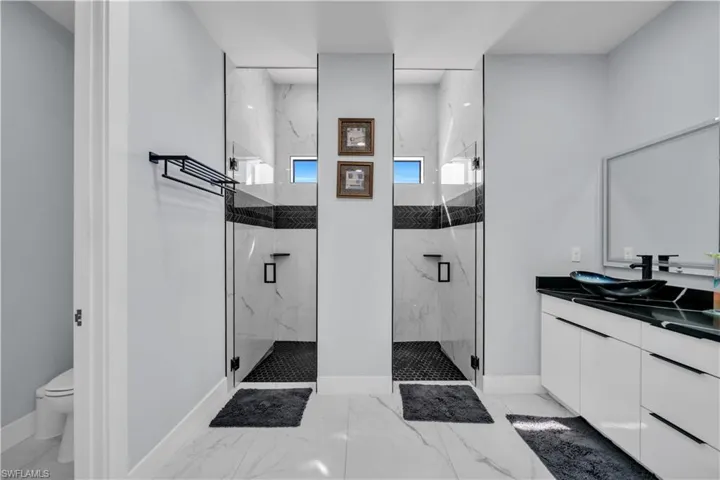 Bathroom with vanity, a marble finish shower, and light marble finish floors