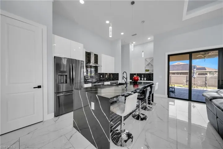 Kitchen with modern cabinets, stainless steel appliances, pendant lighting, white cabinetry, and a breakfast bar
