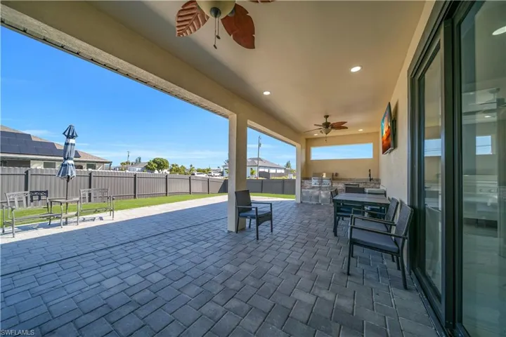 Fenced backyard featuring ceiling fan, exterior kitchen, a patio area, and a residential view