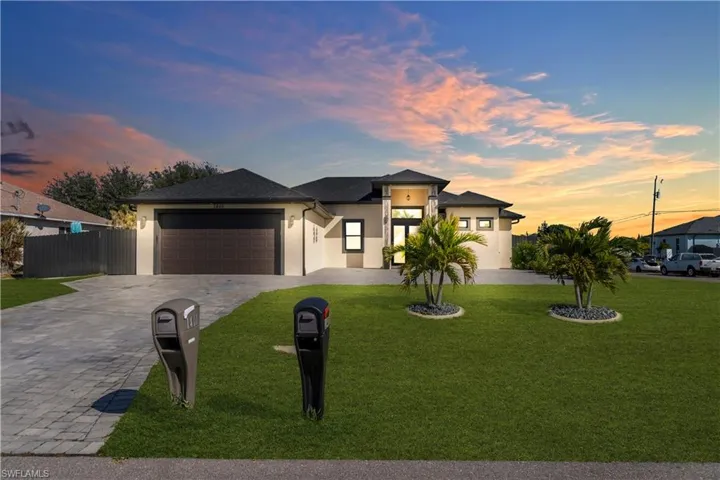 View of front of home featuring stucco siding, decorative driveway, and a garage