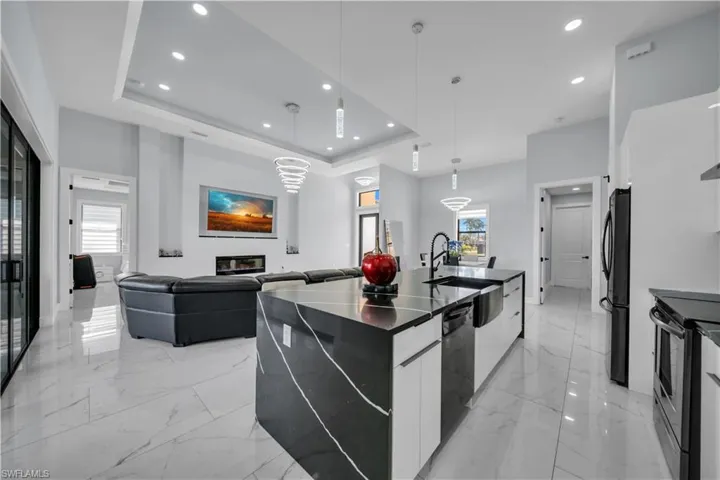 Kitchen featuring a spacious island, decorative light fixtures, modern cabinets, white cabinetry, and light marble finish flooring