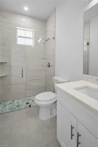 Bathroom featuring vanity, a marble finish shower, and light tile patterned floors