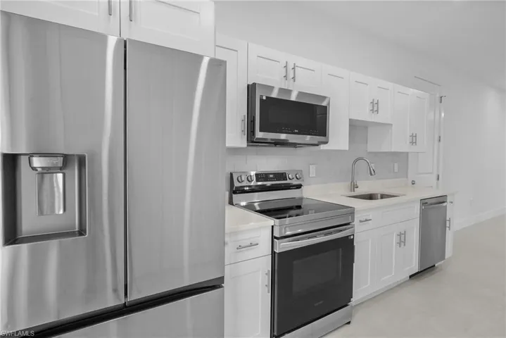 Kitchen with appliances with stainless steel finishes, white cabinetry, and tasteful backsplash