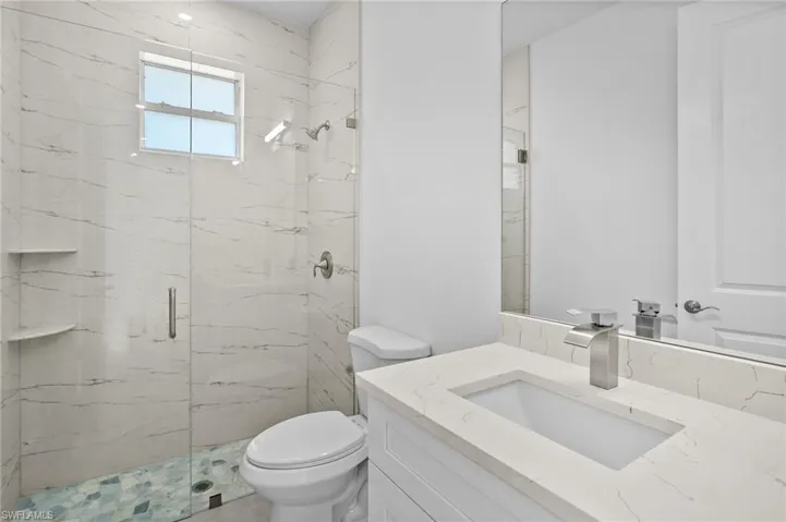 Bathroom with a marble finish shower and vanity