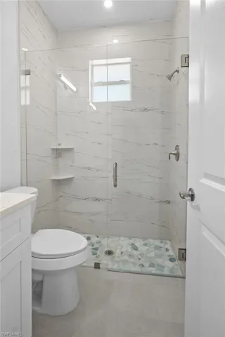 Full bath featuring a marble finish shower, vanity, and light tile patterned floors