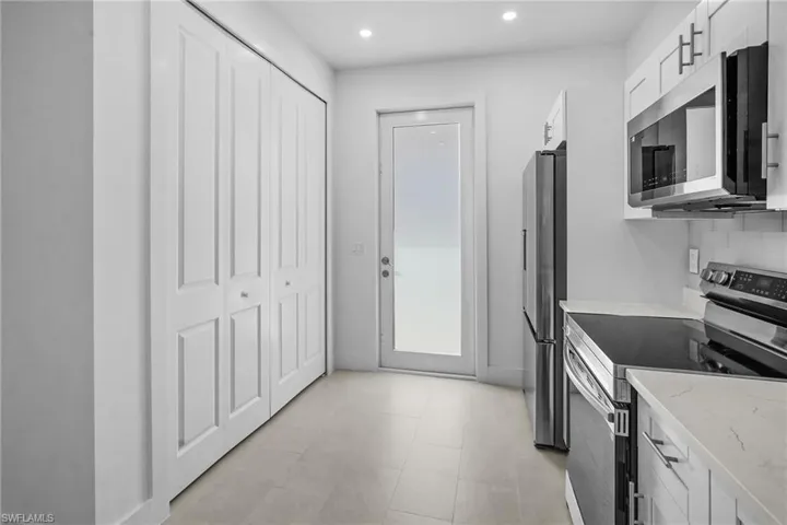 Kitchen featuring appliances with stainless steel finishes, white cabinetry, recessed lighting, and light stone counters