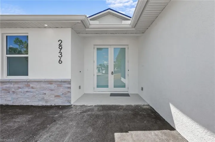 View of exterior entry with stucco siding, stone siding, and french doors