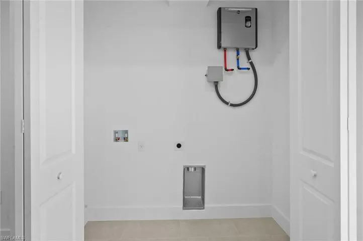 Washroom with tile patterned flooring, hookup for a washing machine, and electric dryer hookup