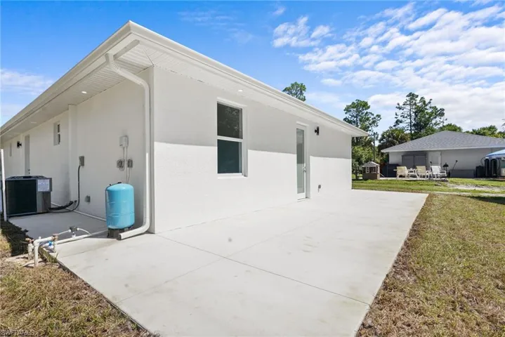 Rear view of property featuring a lawn, stucco siding, a patio area, and lawncare items