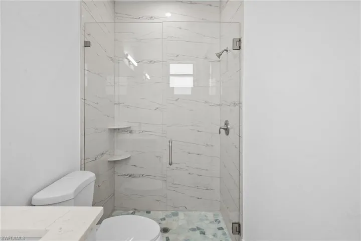 Full bathroom featuring a marble finish shower and vanity