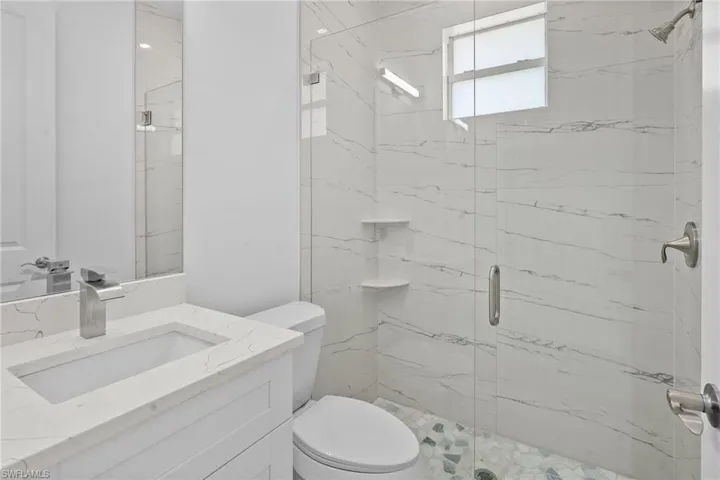 Full bath featuring a marble finish shower and vanity