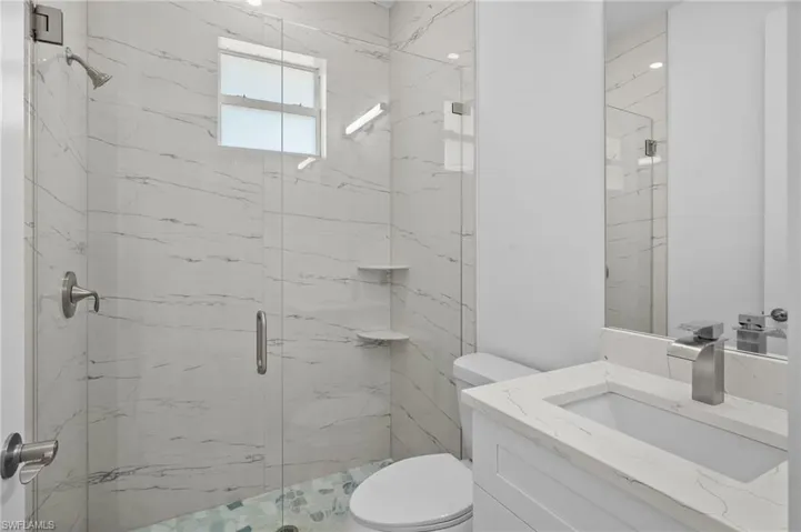 Bathroom featuring a marble finish shower and vanity