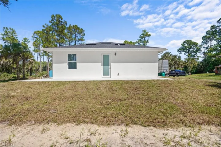 Rear view of property with a yard and stucco siding