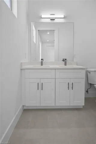 Bathroom featuring double vanity and light tile patterned flooring