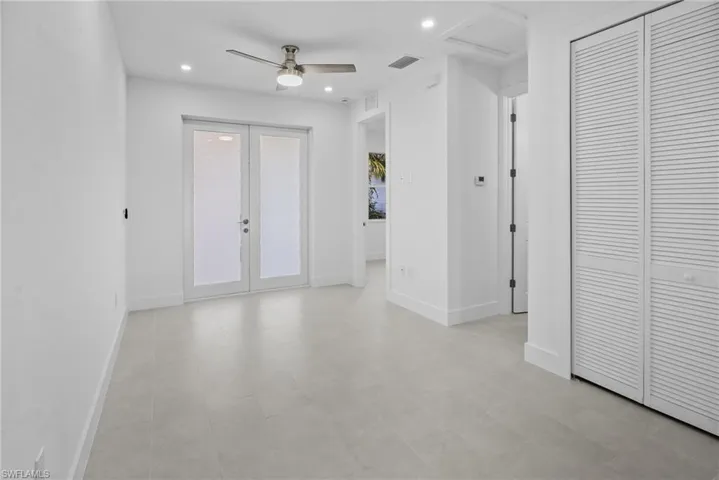 Unfurnished room featuring a ceiling fan, recessed lighting, french doors, and attic access