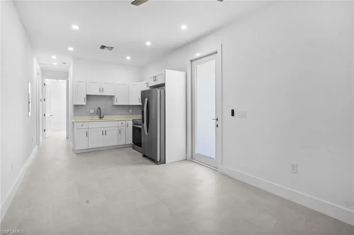 Kitchen featuring light countertops, white cabinets, decorative backsplash, stainless steel appliances, and a ceiling fan