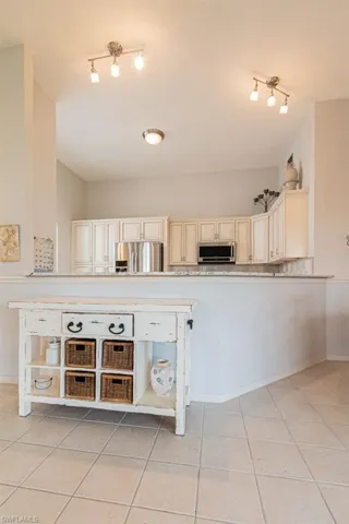 Kitchen featuring appliances with stainless steel finishes, light tile patterned floors, and cream cabinets