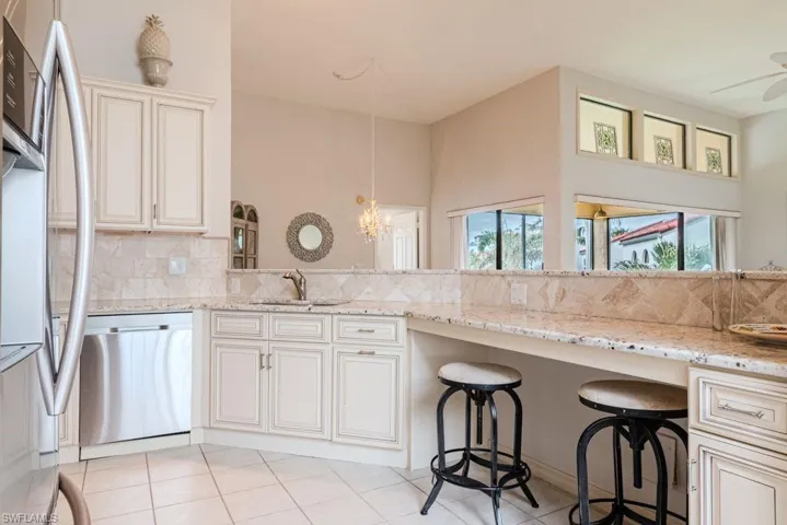 Kitchen featuring sink, hanging light fixtures, decorative backsplash, light stone countertops, and appliances with stainless steel finishes