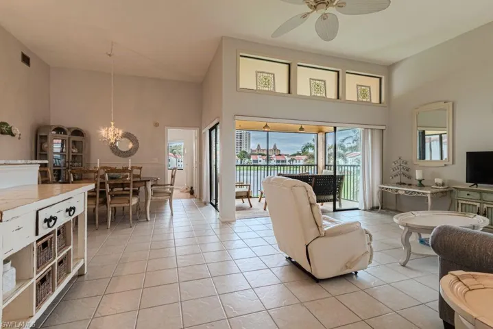 Living room with ceiling fan with notable chandelier, a towering ceiling, and light tile patterned floors
