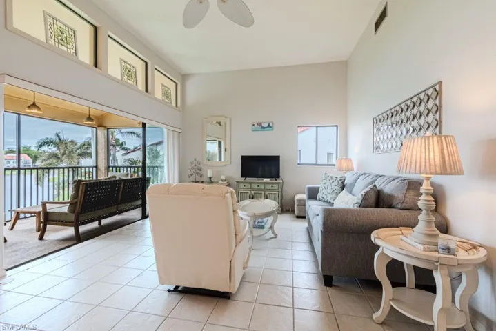 Tiled living room with ceiling fan and high vaulted ceiling